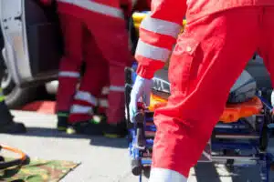 foto ravvicinata di un operatore sanitario che tira su una barella verso l'ambulanza