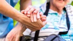 foto ravvicinata della mano di un operatore sanitario che tiene per mano una persona anziana 