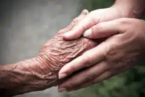 Immagine ravvicinata di due mani che tengono la mano di una persona anziana. 