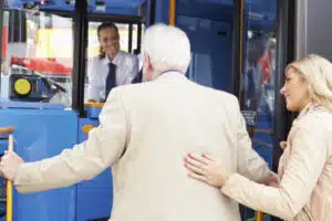 una donna aiuta un uomo anziano a salire su un pullman
