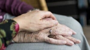mano di una donna che tiene le mani di una persona anziana 